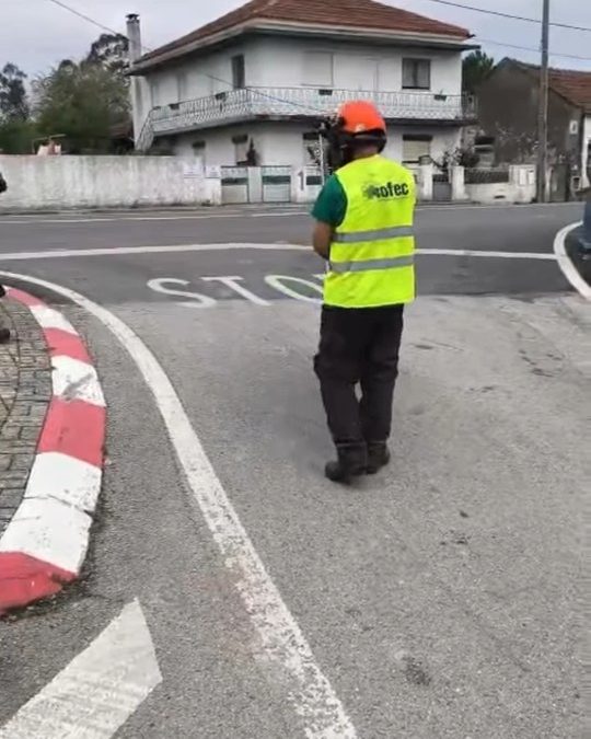 Trabalhador da OFEC de colete refletor e capacete numa rotunda, durante a limpeza